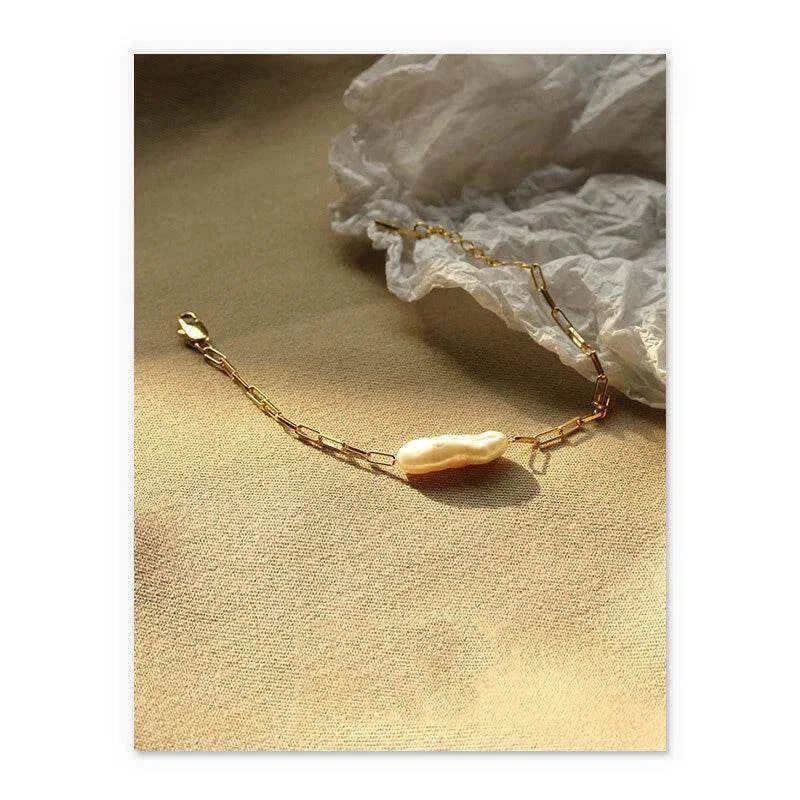 Baroque real pearl bracelet displayed on soft fabric with geometric gold links, capturing elegance and luxury.