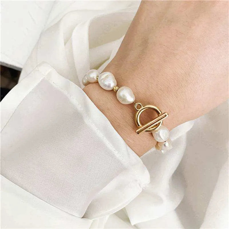 Pearl bracelet with a gold clasp on a wrist against a white background