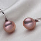 Pair of pink pearl earrings on a light gray fabric background