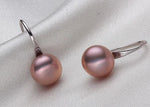 Pair of pink pearl earrings on a light gray fabric background