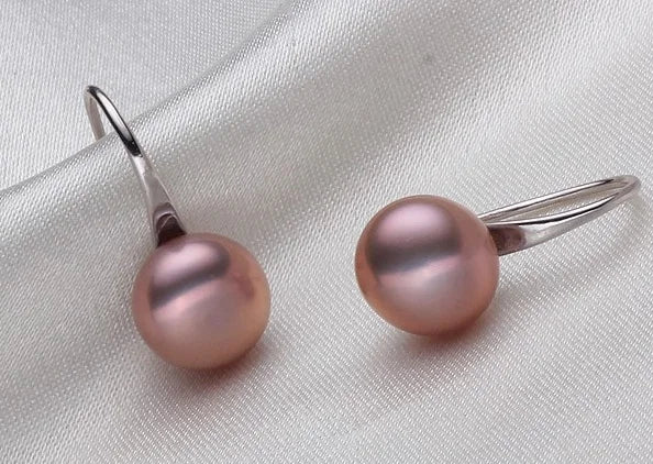 Pair of pink pearl earrings on a light gray fabric background