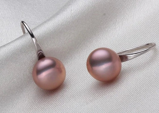 Pair of pink pearl earrings on a light gray fabric background