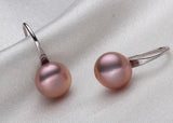 Pair of pink pearl earrings on a light gray fabric background
