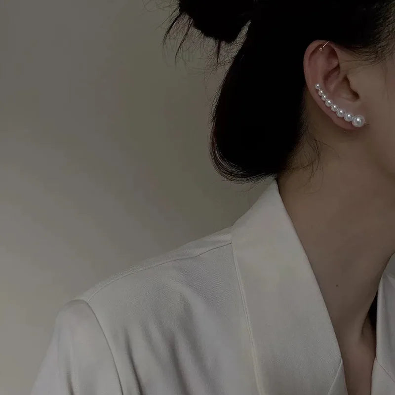 Person wearing pearl earrings with a neutral background