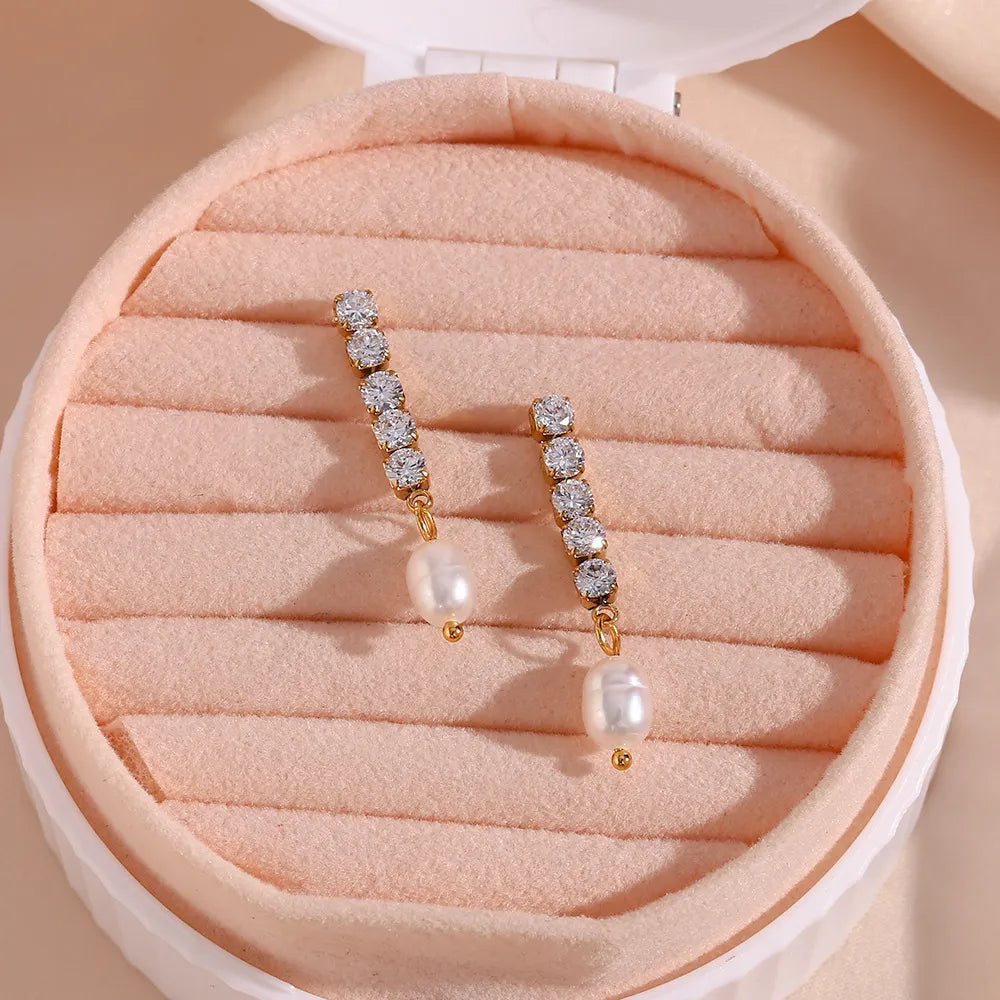Pair of gold earrings with pearls in a pink jewelry box