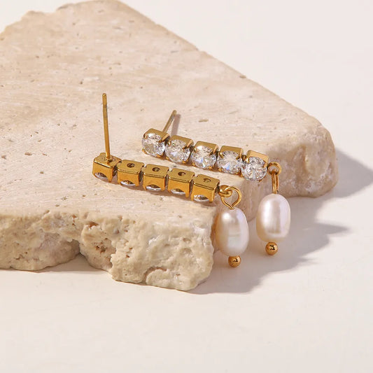Gold and pearl earring on a stone surface