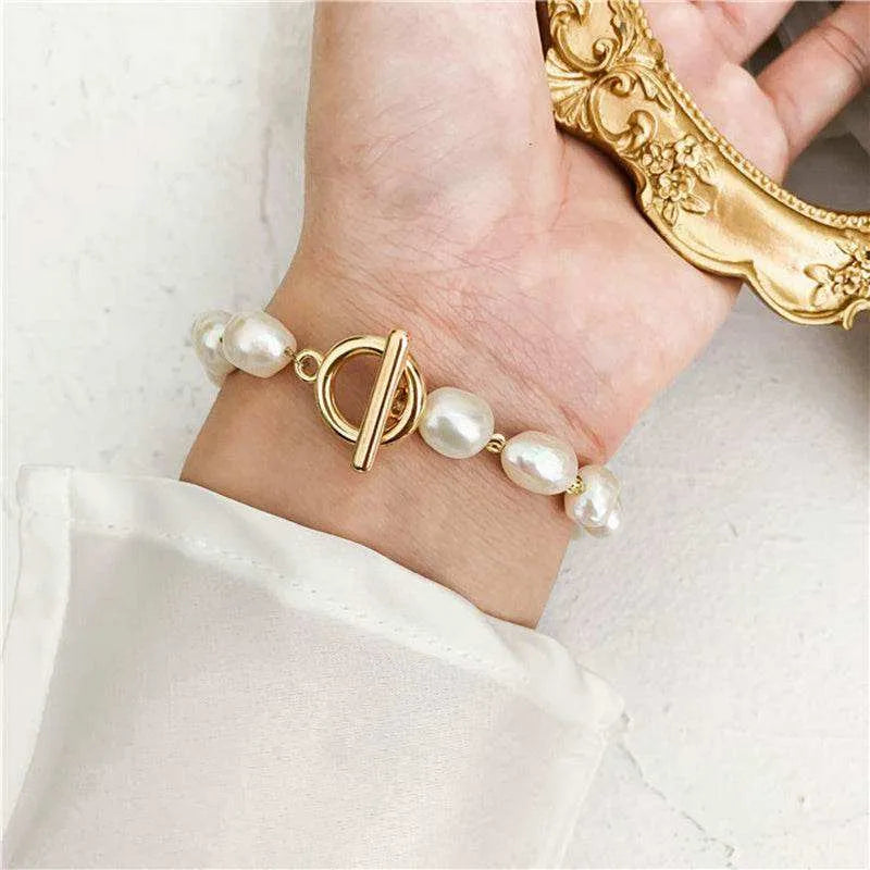 Bracelet with pearls and gold design on a wrist, with a white background