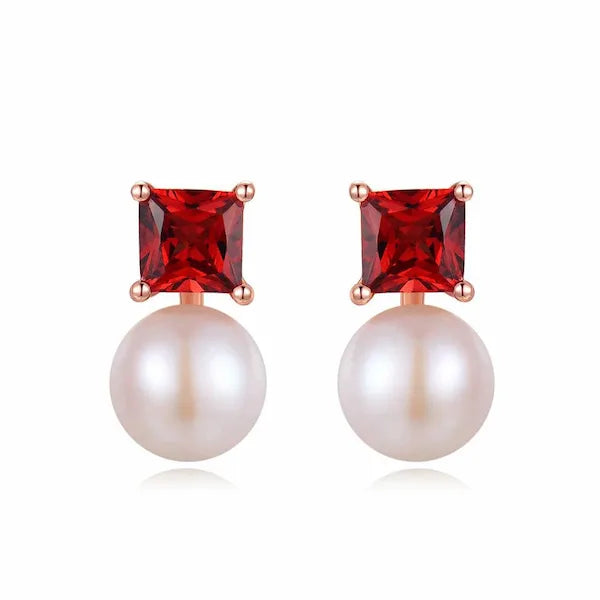 Pair of earrings with red gemstones and pearls on a white background