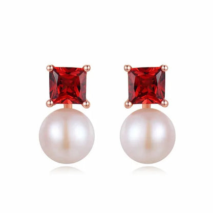 Pair of earrings with red gemstones and pearls on a white background