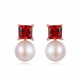 Pair of earrings with red gemstones and pearls on a white background