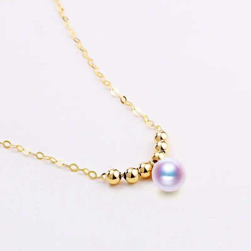 Gold necklace with a single pearl on a white background