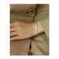 Hand wearing a pearl bracelet on a beige background