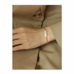 Hand wearing a pearl bracelet on a beige background