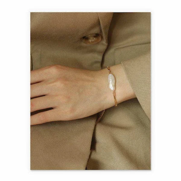 Hand wearing a pearl bracelet on a beige background