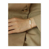 Hand wearing a pearl bracelet on a beige background