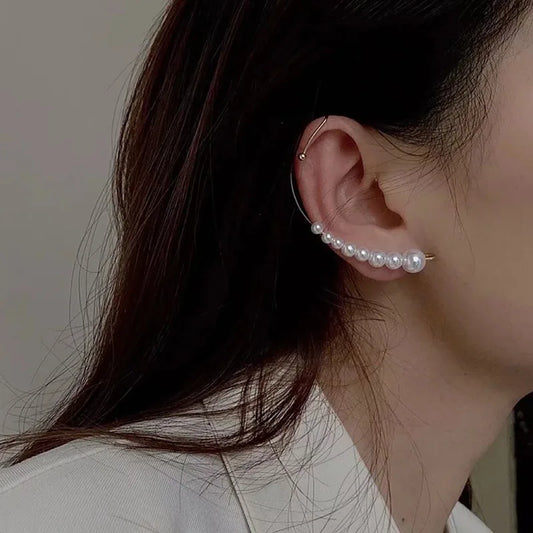 Close-up of an ear wearing a pearl earring with a neutral background