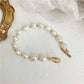 Pearl bracelet with gold clasp on a textured white surface
