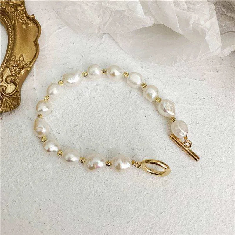 Pearl bracelet with gold clasp on a textured white surface