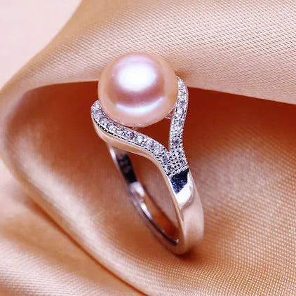 Pearl ring with silver band on a soft pink fabric background