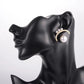 Pearl earring on a black mannequin ear display against a white background