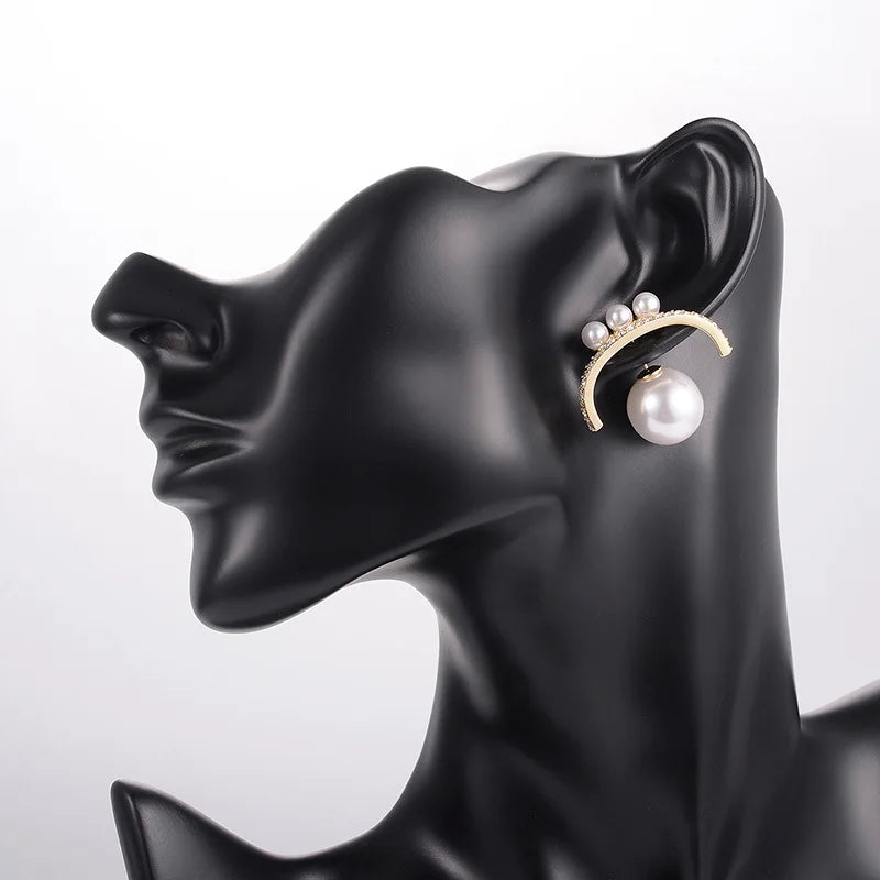 Pearl earring on a black mannequin ear display against a white background