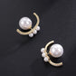 Pair of pearl earrings with gold accents on a black background