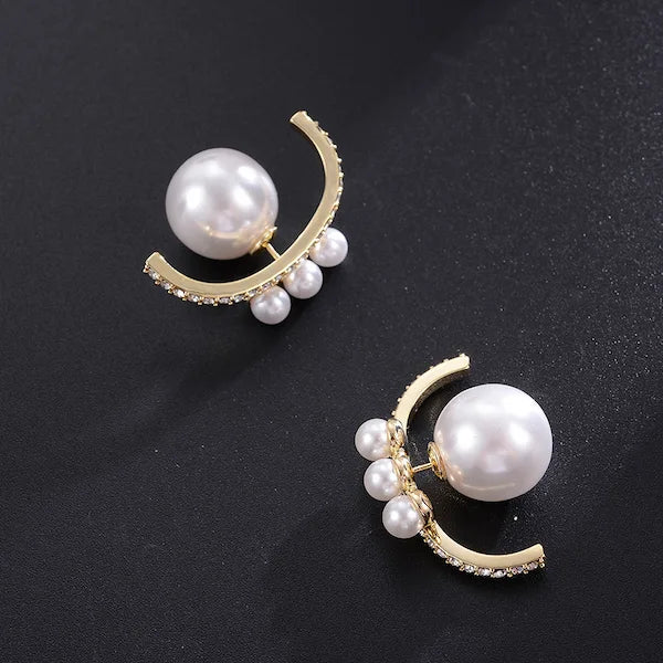 Pair of pearl earrings with gold accents on a black background