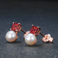 Pair of earrings with red gemstones and pearls on a dark background