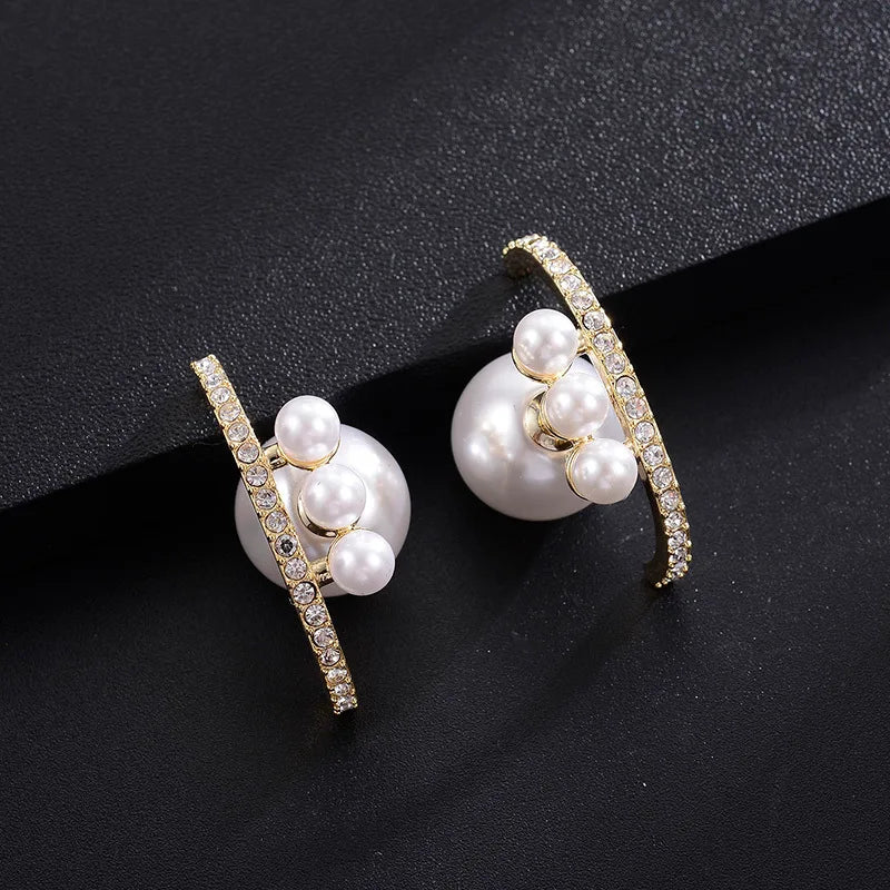 Pair of pearl earrings with gold accents on a black background