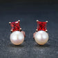 Pair of earrings with red gemstones and pearl-like stones on a dark background