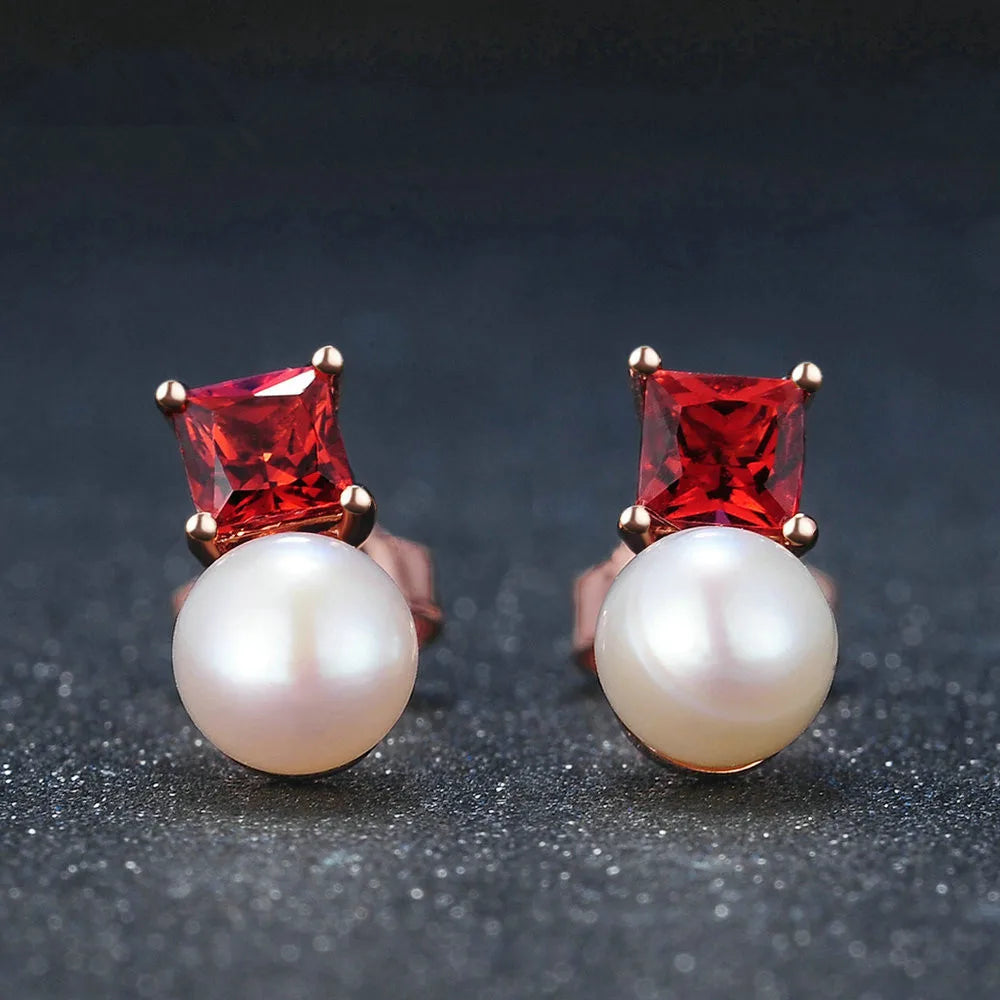 Pair of earrings with red gemstones and pearl-like stones on a dark background