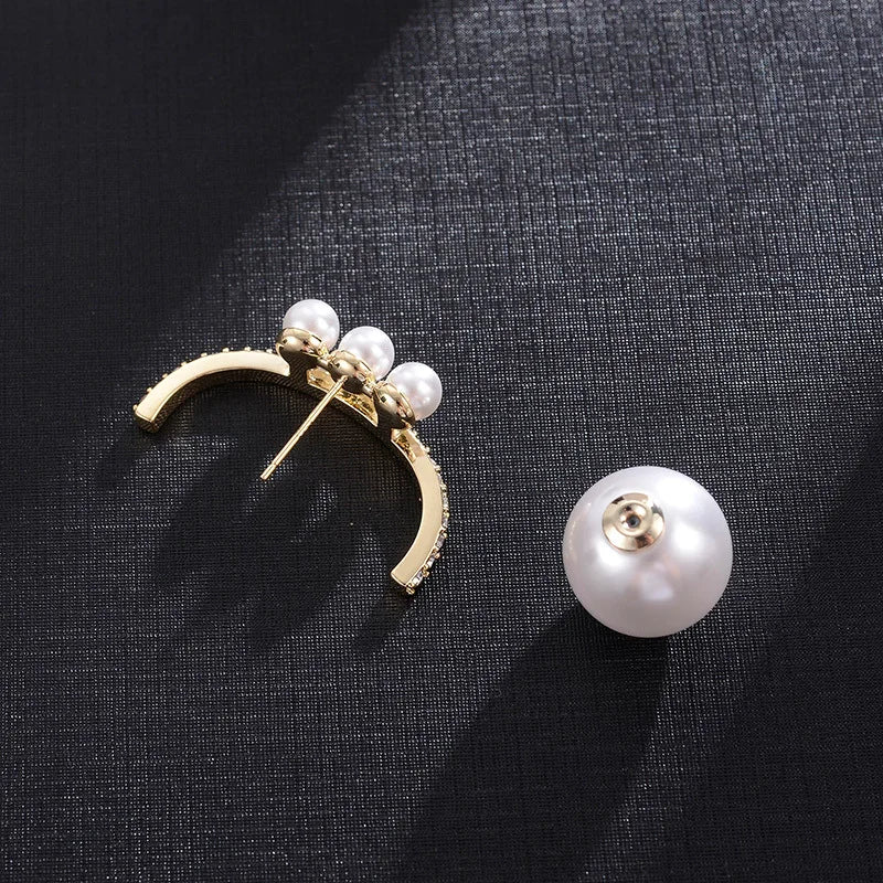 Gold earring with pearls on a dark fabric background
