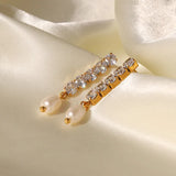 Gold earrings with pearls and crystals on a beige fabric background