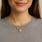 Close-up of a person wearing a gold necklace with a pearl pendant.