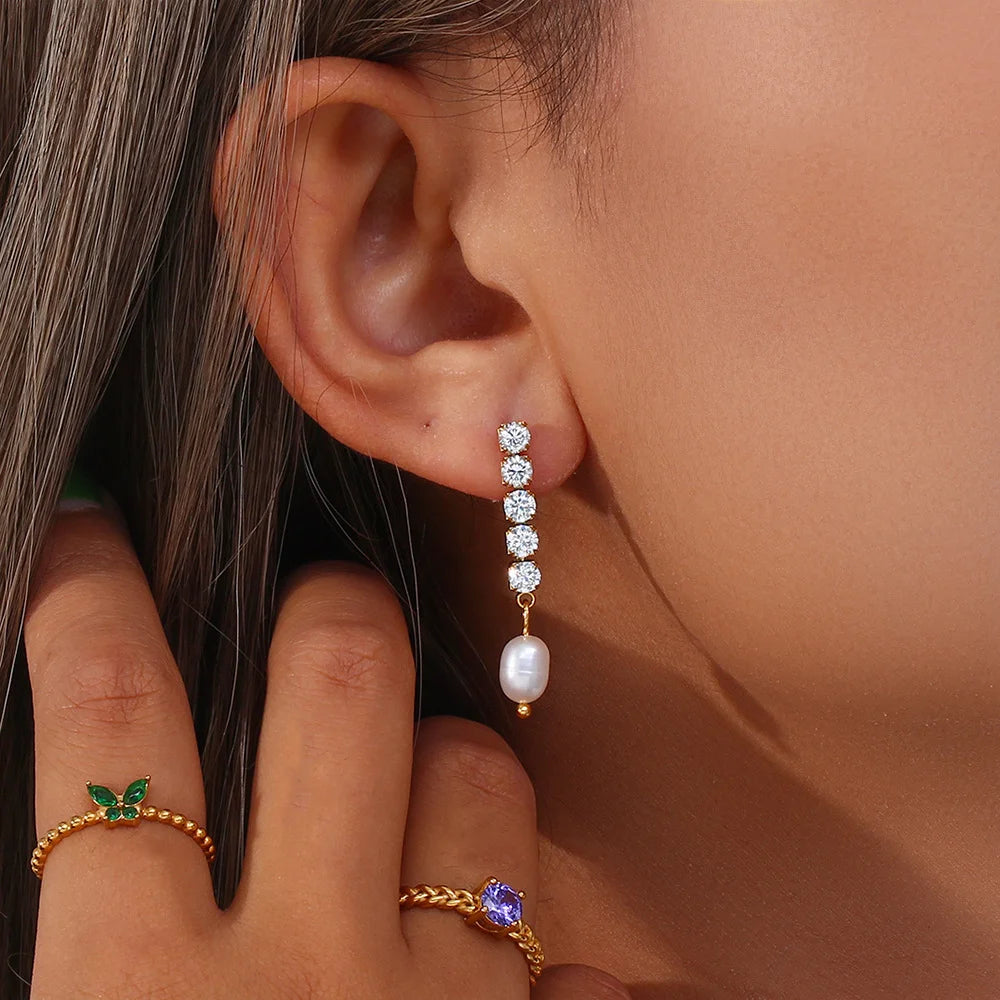 Close-up of an ear wearing a diamond and pearl earring with a hand holding the ear.