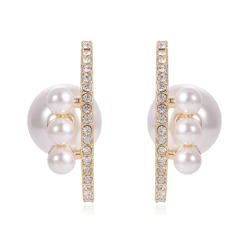 Pair of pearl earrings with gold and crystal accents on a white background